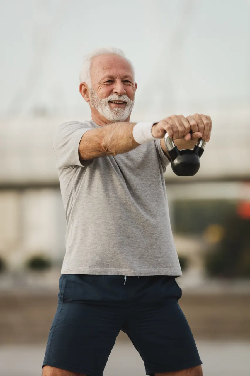 An older man training with a kettlebell outdoors