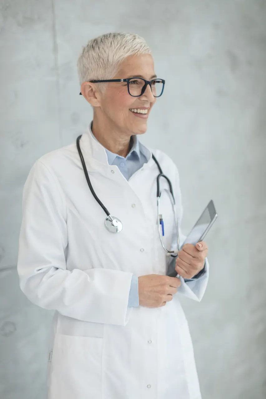 A smiling physician in a white coat holding a tablet